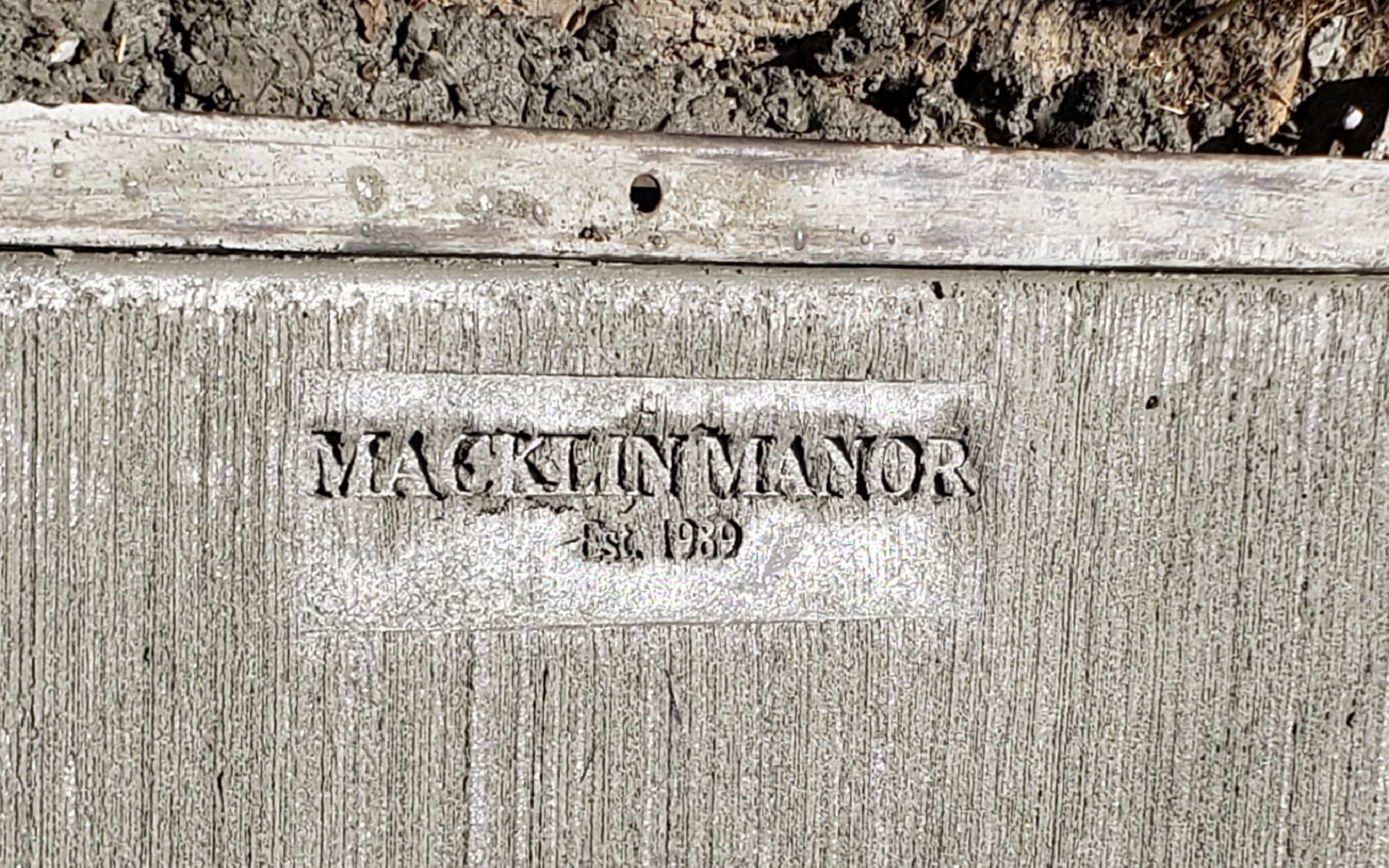A section of concrete stamped with the phrase "Macklin Manor. Est 1989"